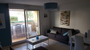 A living room with a sofa, a coffee table, and a dining area with a table and chairs. - Very nice spacious and bright apartment T3 any comfort (terrace 25m2) (Hyères)