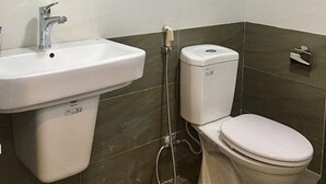 A bathroom with a sink, toilet, and a wall-mounted air purifier. - V House 1 Serviced Apartment (Hanoi)