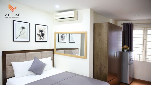 A bedroom with a bed, a wardrobe, an air conditioner, and a refrigerator. - V House 1 Serviced Apartment (Hanoi)