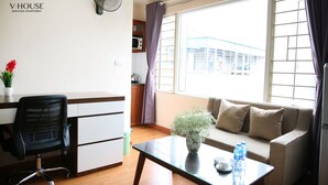 A serviced apartment with a kitchenette, a sofa, a glass coffee table, and a desk with a chair. - V House 1 Serviced Apartment (Hanoi)