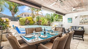 An outdoor dining area with a pool, wicker furniture, and a view of a house and greenery. - 3 Bed Villa with Private Pool, West Coast Barbados (Porters St James)