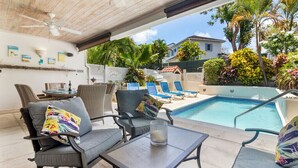 A covered outdoor area with a pool, lounge chairs, and a table with a candle. - 3 Bed Villa with Private Pool, West Coast Barbados (Porters St James)