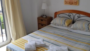 Un lit bien fait, avec une literie à rayures, une lampe de chevet et une décoration murale représentant un globe terrestre.