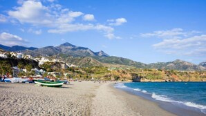 Une plage avec des bateaux, un ciel dégagé et des montagnes en arrière-plan.