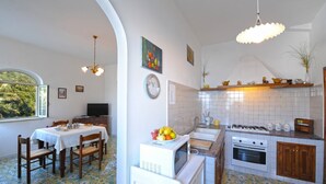 Una cucina con zona pranzo, zoccolo di piastrelle bianche e una finestra con vista.