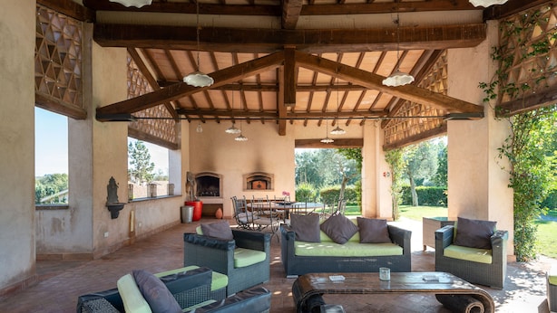 Ein Patio im Freien mit Korbmöbeln, einem Kamin und Blick auf den Garten.
