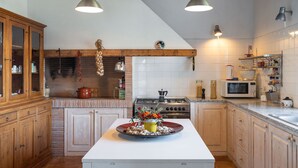 Eine Küche mit Holzausstattung, einer zentralen Kochinsel mit Blumenarrangement, einem Herd und einer Mikrowelle.