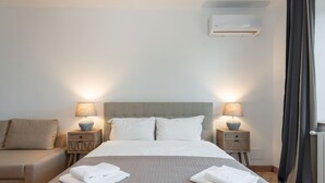 Ein Hotelzimmer mit einem Bett, zwei Nachttischen mit Lampen, einem Sofa und einer Klimaanlage.