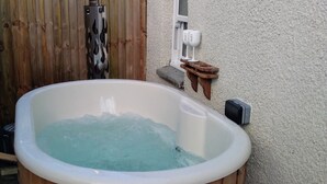 A wooden hot tub with a white interior, a bottle of champagne, and a watermelon-patterned cloth in a wicker basket. - Cottage sleeps 4 with private hot tub. Edinburgh festival less than 1hr away.  (Kinross)