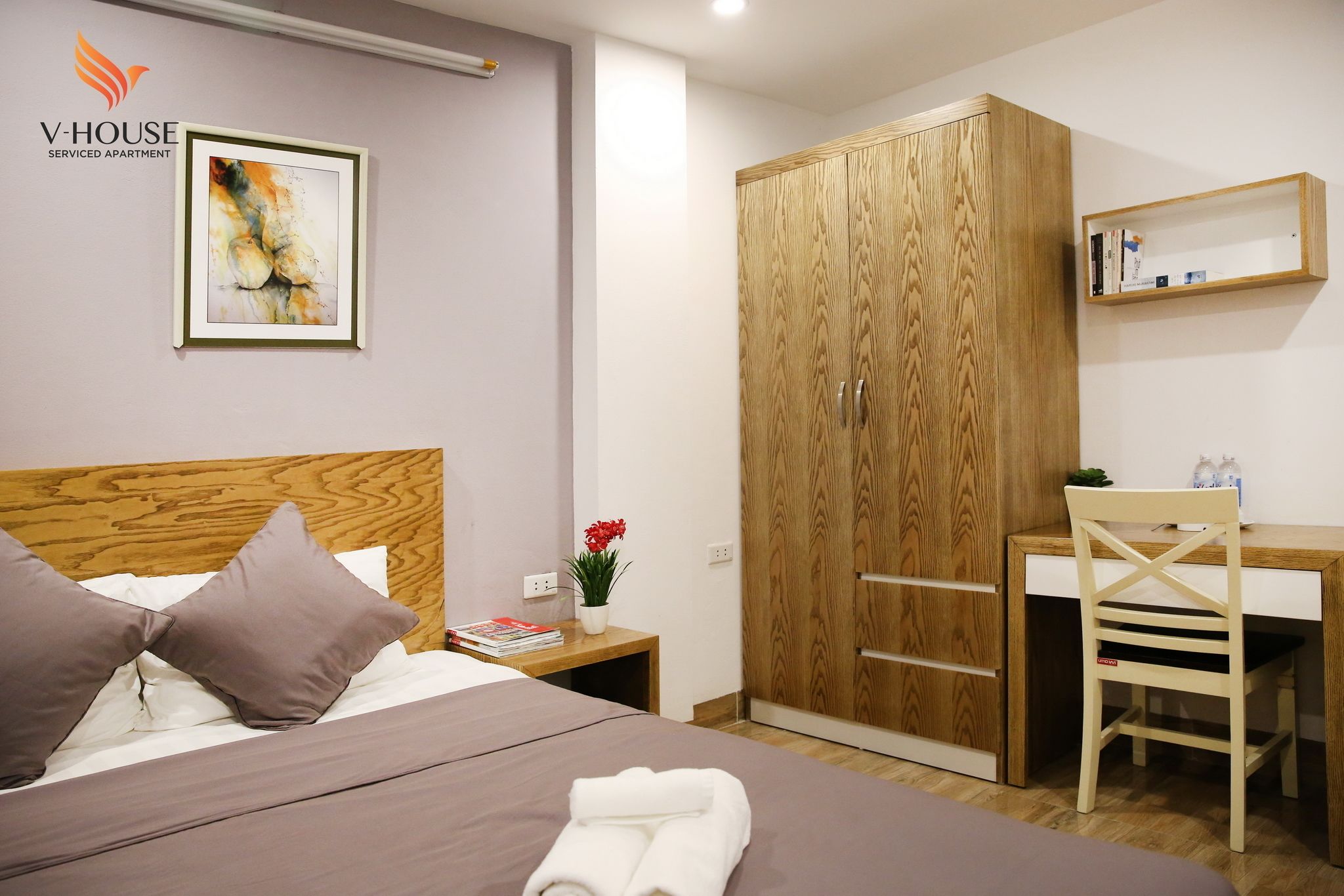 Un dormitorio con un armario de madera, un escritorio y una cama con almohadas.