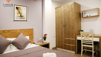 Un dormitorio con un armario de madera, un escritorio y una cama con almohadas.