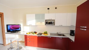 Een moderne keuken met een ingebouwde magnetron, een koffiezetapparaat en een televisie op een standaard.
