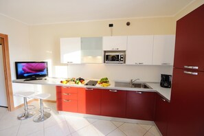 Eine moderne Küche mit Einbau-Mikrowelle, einer Kaffeemaschine und einem Fernseher auf einem Lowboard.