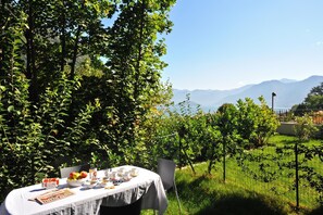 An outdoor dining table with a view of mountains and a grassy area.