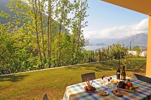 Ein Tisch im Freien mit Blick auf eine gebirgige Landschaft, bedeckt mit einer Tischdecke, mit verschiedenen Speisen und Getränken.