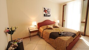 Een hotelkamer met een bed, twee nachtkastjes, een wanddecoratie en een raam met gordijnen.