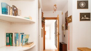 A hallway with bookshelves on both sides, a wooden door at the end, and a small table with a basket on the right. - Carabeillo 13 Apartments by Casasol (Nerja)