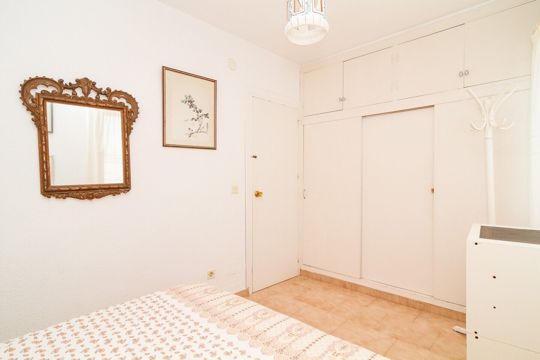 Une chambre à coucher avec un lit, une armoire, un miroir et un tableau encadré accroché au mur.