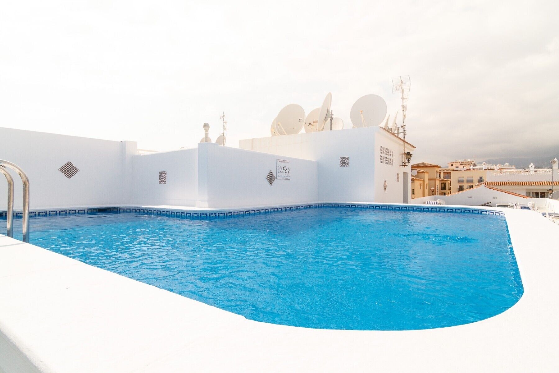 A rooftop swimming pool with a clear view of the surrounding buildings and satellite dishes.