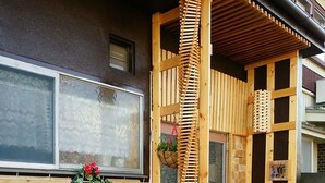 Ett utomhusområde med trägolv, ett trästaket, planterade blommor och en liten trädgård.