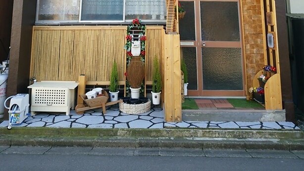 En modern byggnad i två våningar med en mörk fasad, en träbeklädd övervåning och en täckt entré med en träpergola.