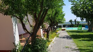 Un sentier bordé d’arbres et un espace piscine.