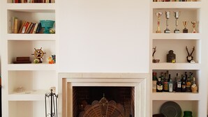 Un salon doté d’une cheminée, de bibliothèques et de divers objets décoratifs.