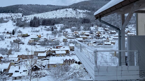 Ein verschneites Dorf mit Häusern und einem Berg im Hintergrund.