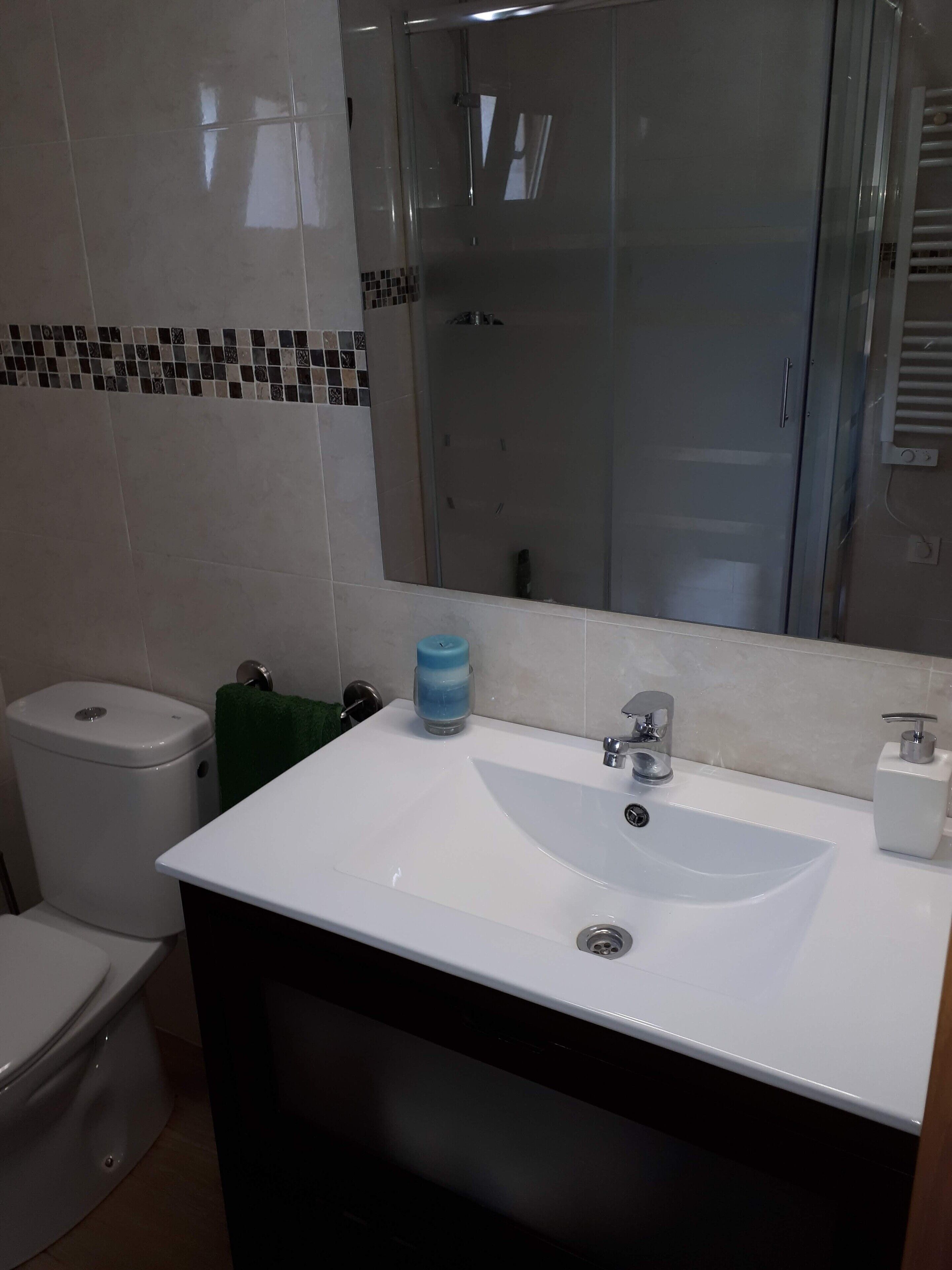 A bathroom with a white sink, a toilet, and a shower.