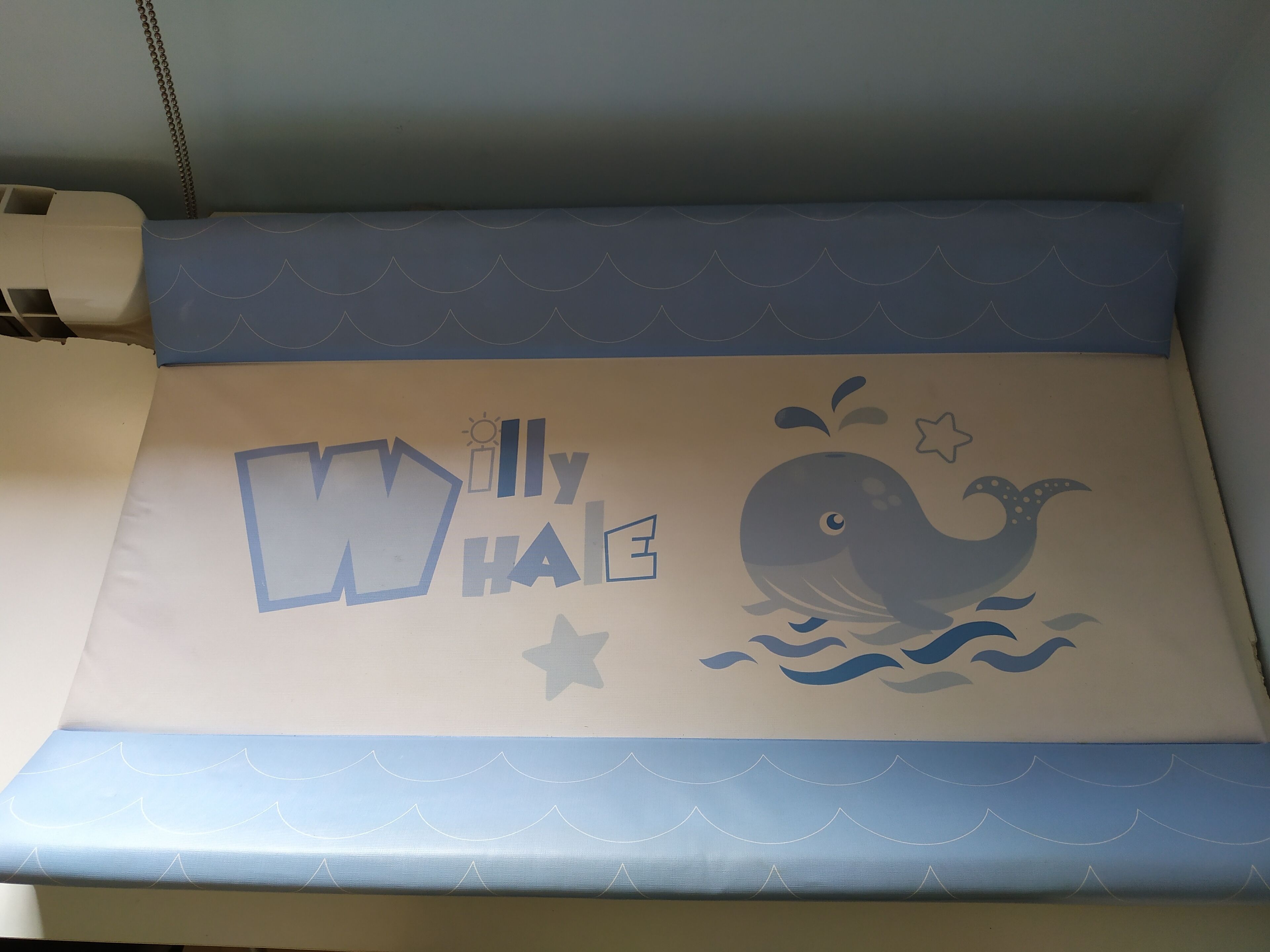 Un lit au motif bleu et blanc sur le thème de la marine, avec des motifs représentant des baleines et des vagues.
