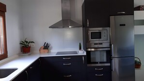 A modern kitchen with dark cabinets, stainless steel appliances, and a white countertop. - Rural house with garden and terrace between two natural parks. (Igorre)