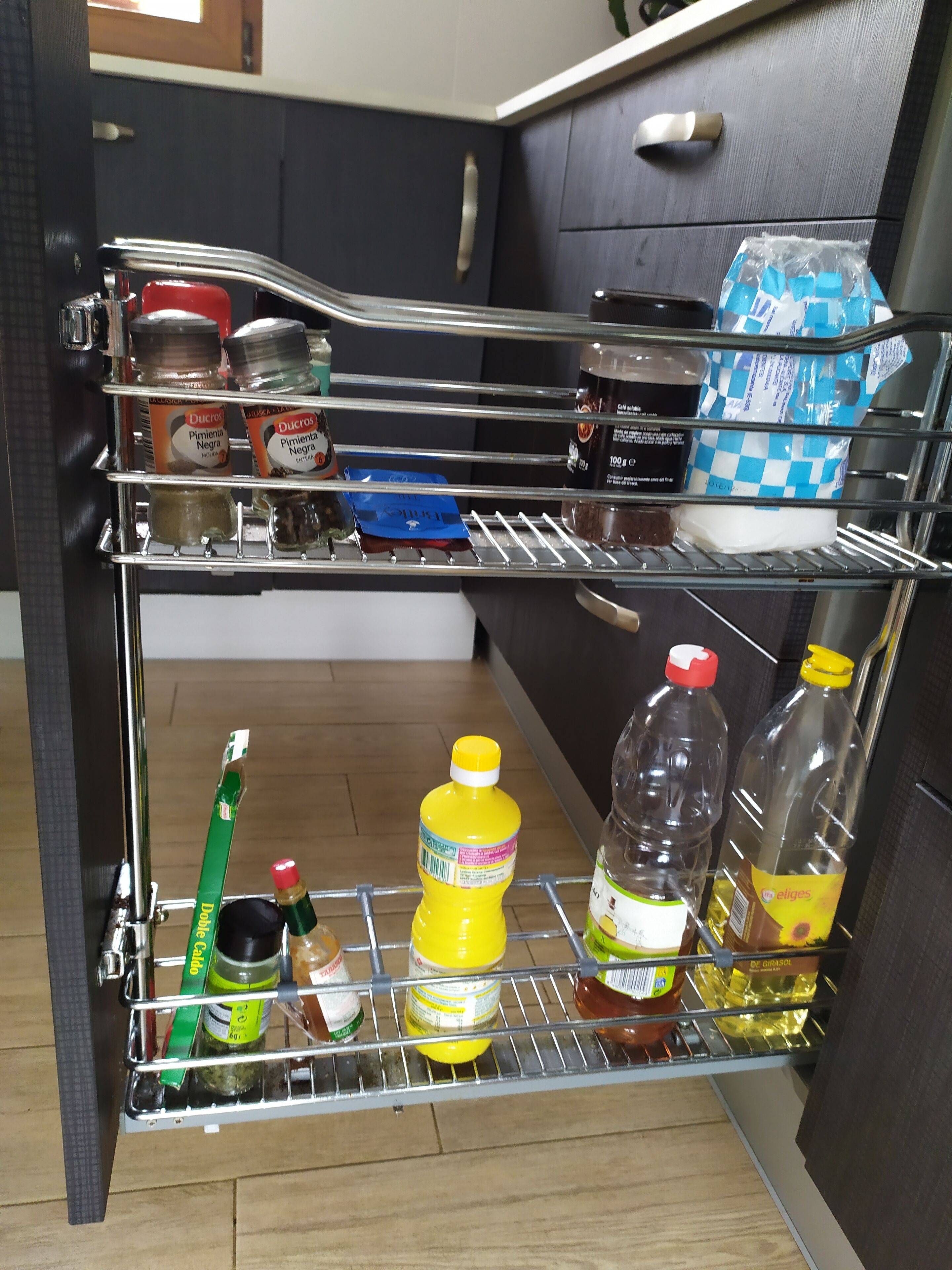 A kitchen with a metal shelf unit holding various kitchen items.
