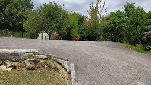 A rural road with a grassy area on the left and trees on both sides. - Rural house with garden and terrace between two natural parks. (Igorre)