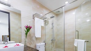 Un baño moderno con tocador de mármol, ducha con mampara de vidrio y un inodoro.