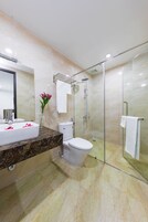 Un baño moderno con tocador de mármol, ducha con mampara de vidrio y un inodoro.