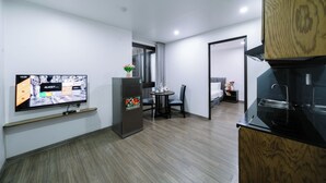 Habitación de hotel compacta con televisión de pantalla plana, refrigerador, zona de comedor y kitchenette.