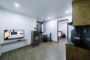 Habitación de hotel compacta con televisión de pantalla plana, refrigerador, zona de comedor y kitchenette.