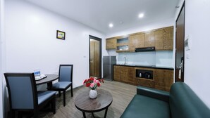 Un espacio habitable compacto con comedor, kitchenette y un sofá verde.