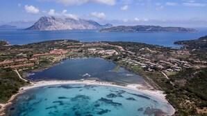 Vue aérienne d’une station balnéaire dotée d’un grand lac, d’une plage et bordée de montagnes.