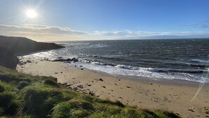 Ein Strand mit Wellen, blauem Himmel und Sonnenschein.