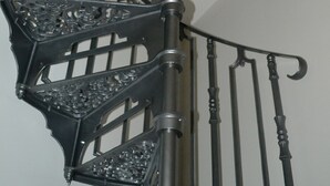 Eine Wendeltreppe mit aufwendiger Metallgeländerung und einer zentralen Säule.