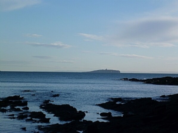 A coastal scene with a rocky shoreline and calm sea.