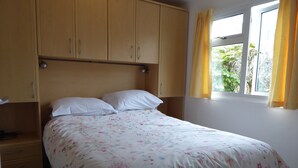 Quarto com cama, guarda-roupa de madeira e janela com cortinas.