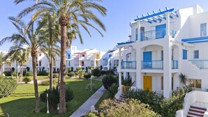 A resort with white buildings, blue balconies, and palm trees. - 111 Alberca 8-3 (Denia)