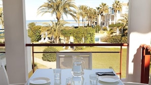 A table set for two with a clear view of the sea and palm trees in the background. - 111 Alberca 8-3 (Denia)