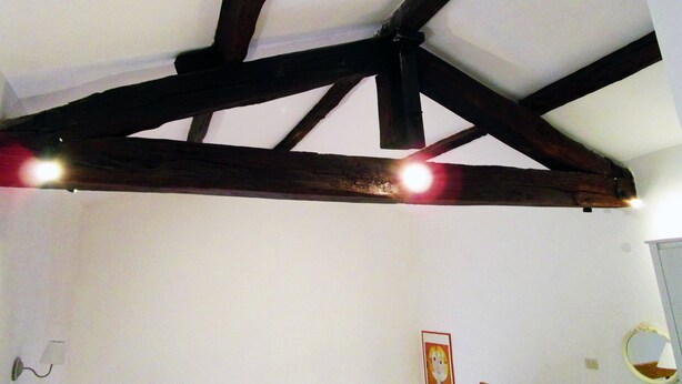 A room with exposed wooden beams on the ceiling and a framed picture on the wall.