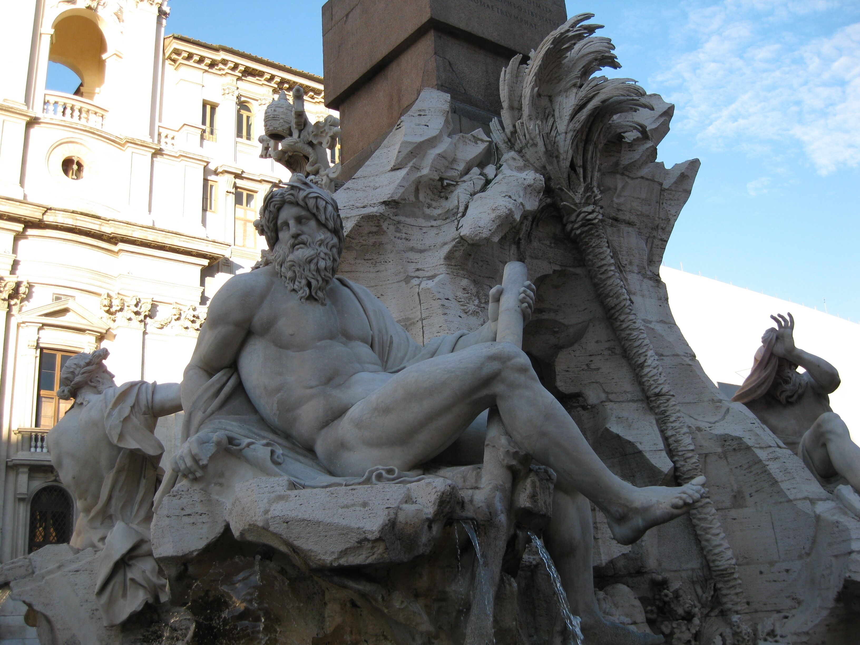 A classical sculpture of a seated man with a beard, surrounded by ornate architectural elements.
