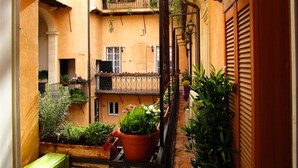 A narrow courtyard with balconies, potted plants, and a small table.