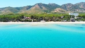 A coastal hotel with a beach view, mountains in the background, and clear turquoise waters. - A Perfect Starting Point for Coastal Exploration for family or friends. (Santa Margherita di Pula)