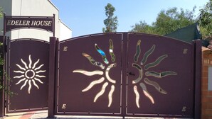 Une entrée fermée par un portail orné d’un motif solaire, avec l’inscription « Edeler House » au-dessus.